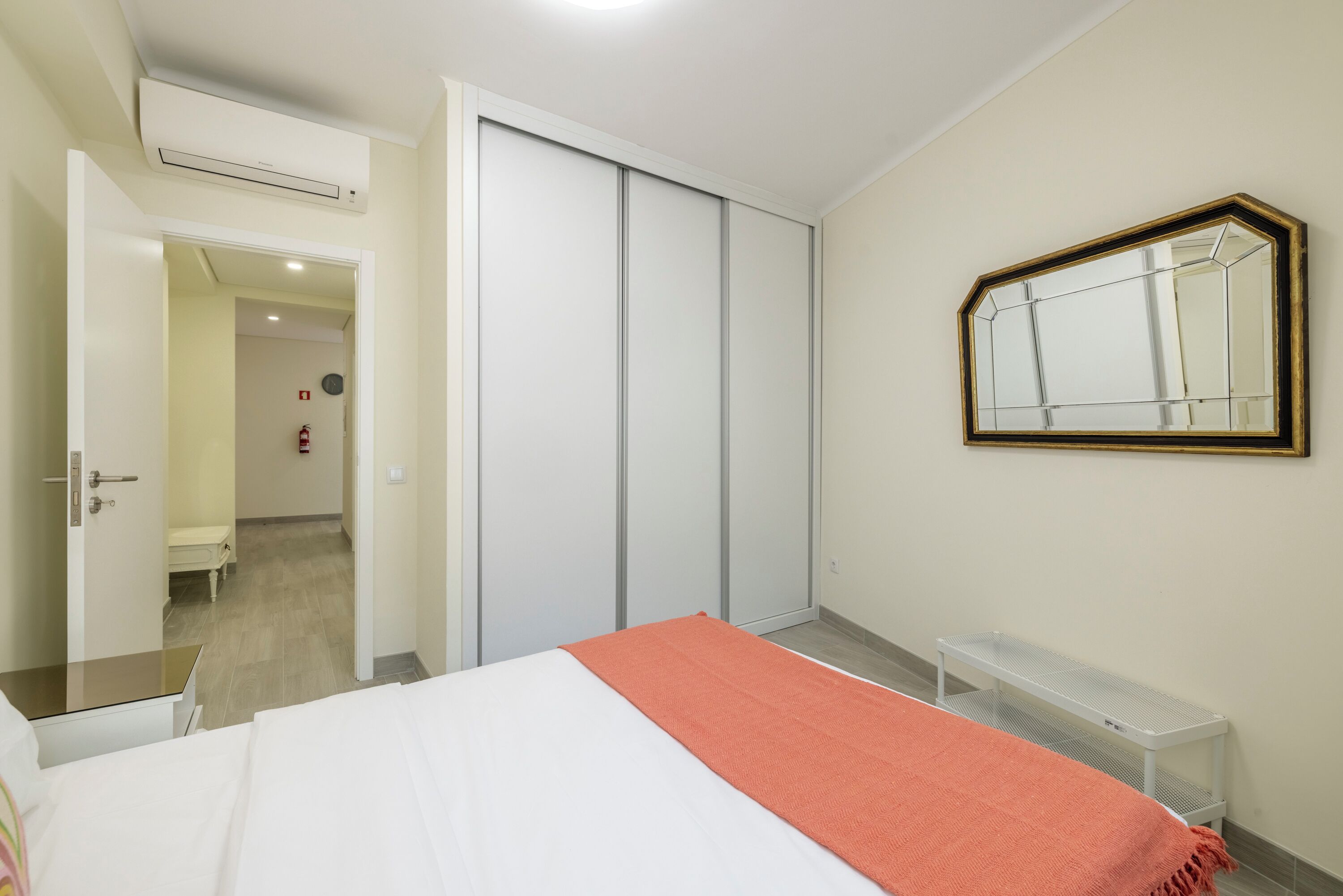 Een hotelkamer met een bed, een kledingkast, een spiegel en een witte bank.