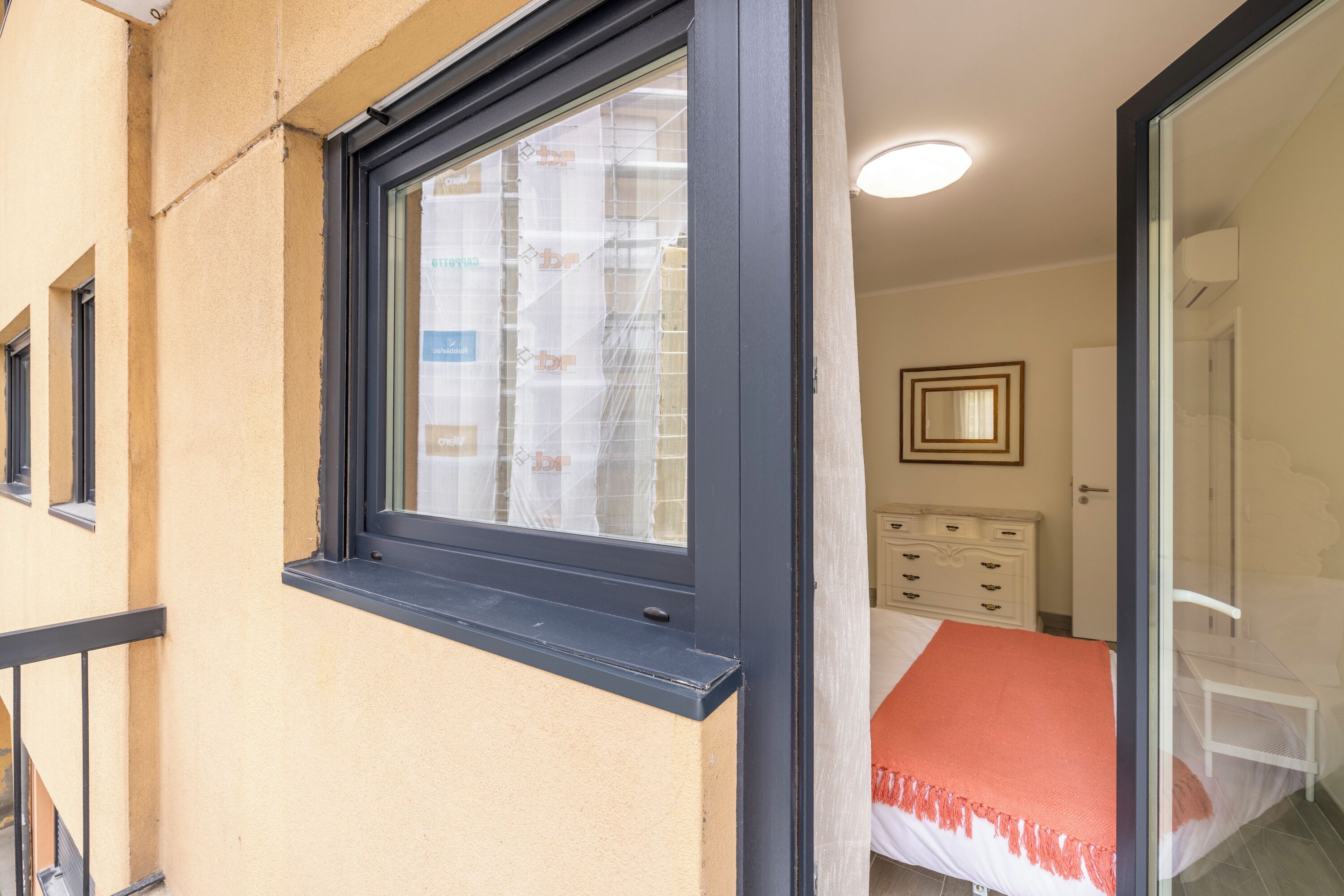 Ein Schlafzimmer mit einem Bett, einem Schminktisch und einem Fenster mit Jalousien.