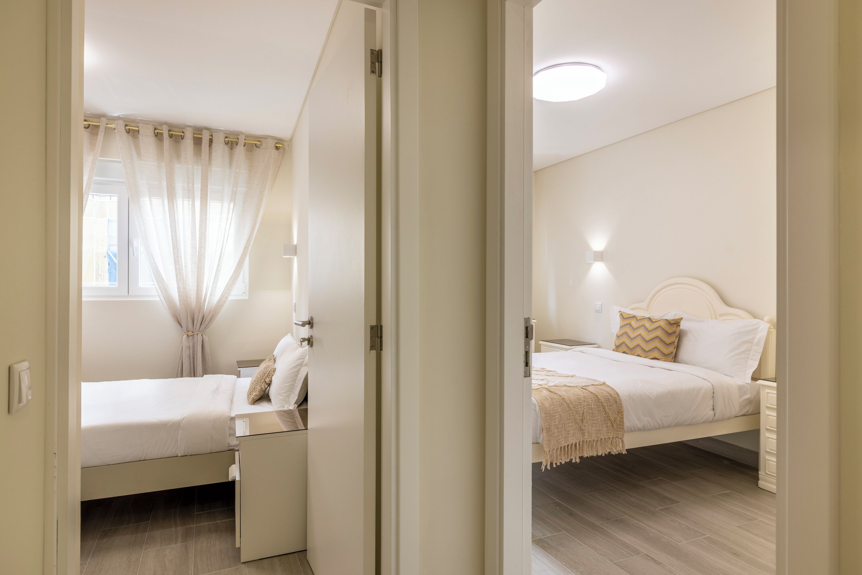 A bedroom with a bed, bedside table, and a window with curtains.