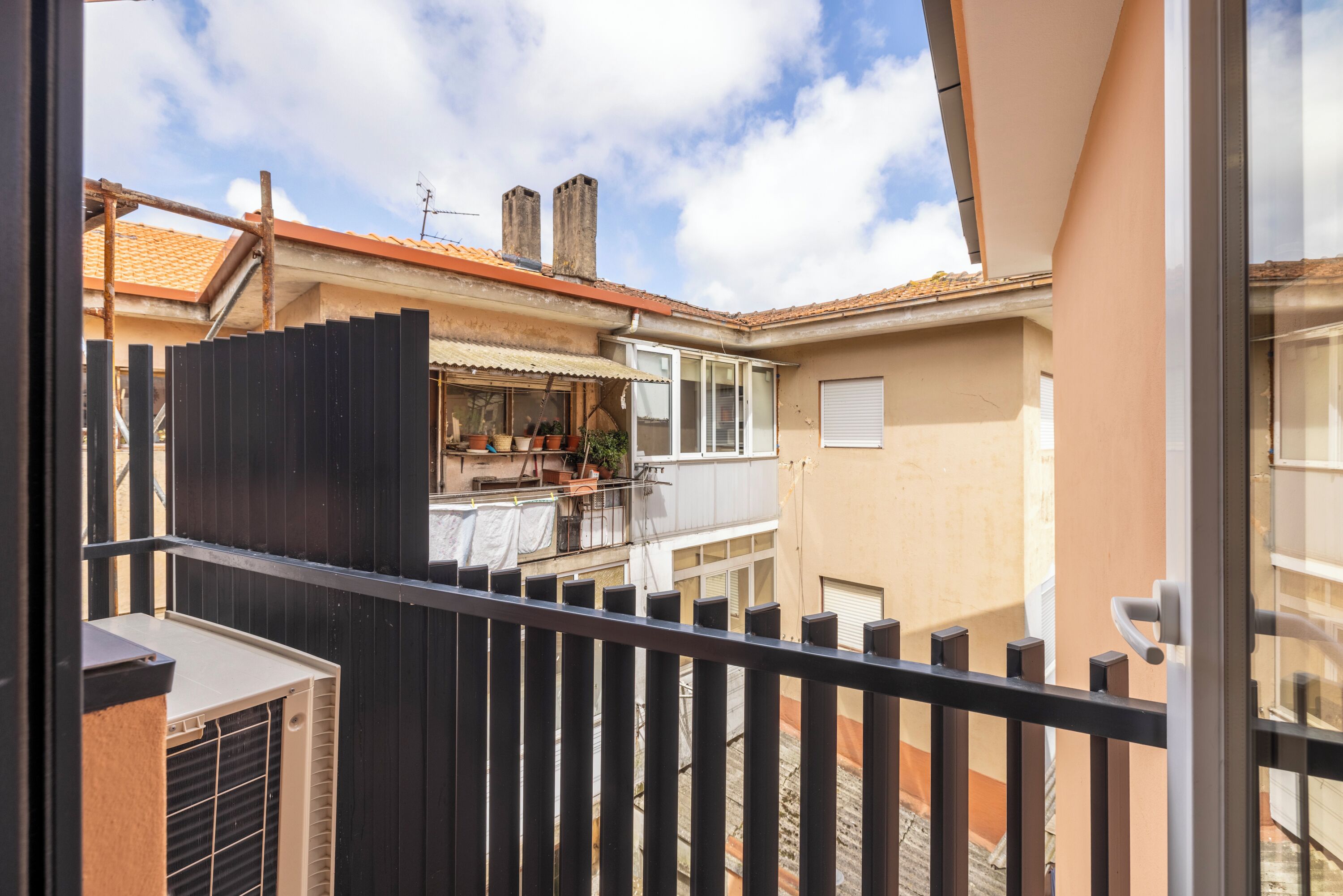 A residential building with a balcony, a small outdoor seating area, and a visible chimney.