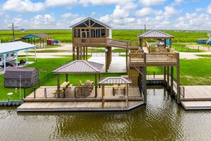 A waterfront property with multiple wooden decks, a central elevated structure, and outdoor seating areas.
