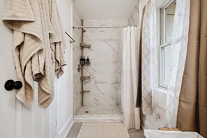 A bathroom with a shower, a towel rack, and a window. - Cozy guest suite w/ kitchen & parking (Pensacola)