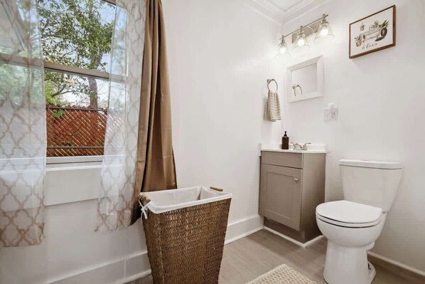 Une salle de bain équipée de toilettes, d’un lavabo et d’un panier à linge en osier.