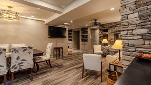 A spacious living area with a stone wall, wooden flooring, and modern furniture. - 7BR/10BA Five Points Private Gathering Home | Sleeps 26, Theatre, Golf Sim, Elevator & Outdoor Areas (Raleigh)