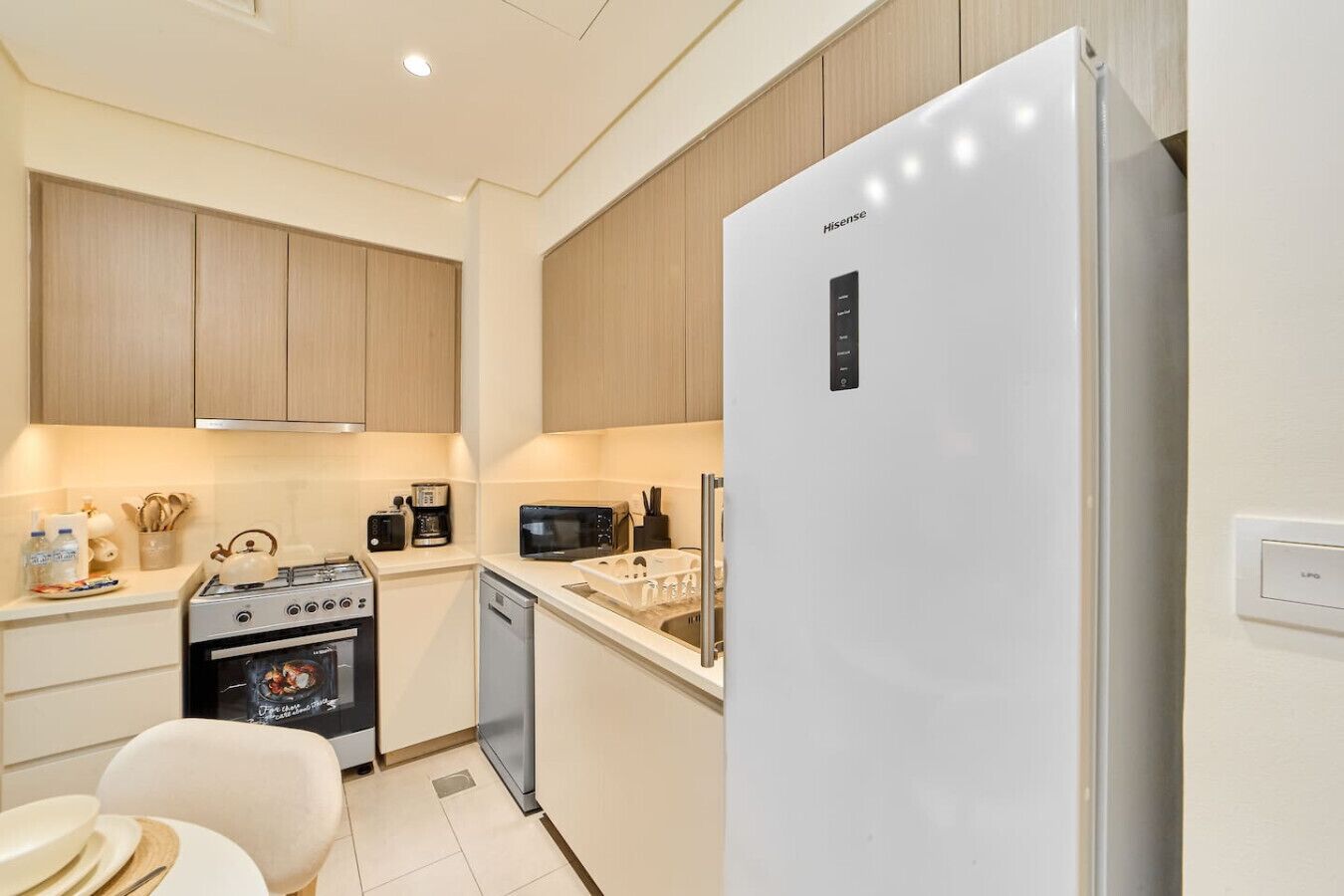 Une cuisine moderne avec un réfrigérateur blanc, des appareils en acier inoxydable, des meubles en bois et un aménagement compact.