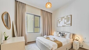 Moderni hotellihuone, jossa on suuri sänky, yöpöytä lampun kanssa, peili ja ikkuna, jossa on verhot.