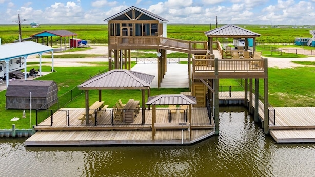 A waterfront property with multiple wooden decks, a central wooden structure, and outdoor seating areas. - Mabry 1 Bedroom Home (Port Bolivar)