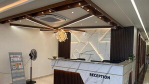 A reception desk with a marble top, a modern chandelier, and a wall with geometric patterns. - Hotel Pasupala Inn (Anantapur)