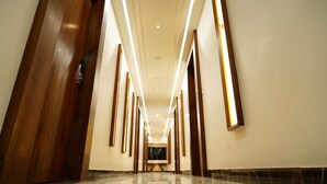A long, narrow hallway with wooden doors and walls, featuring a modern light fixture and a marble floor. - Hotel Pasupala Inn (Anantapur)