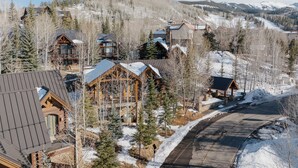 A lodge with multiple wooden cabins, a ski slope in the background, and a clear sky. - Cozy Cabin by InvitedHome | Theater Room, Bunk Room, Vaulted Ceilings (Mountain Village)