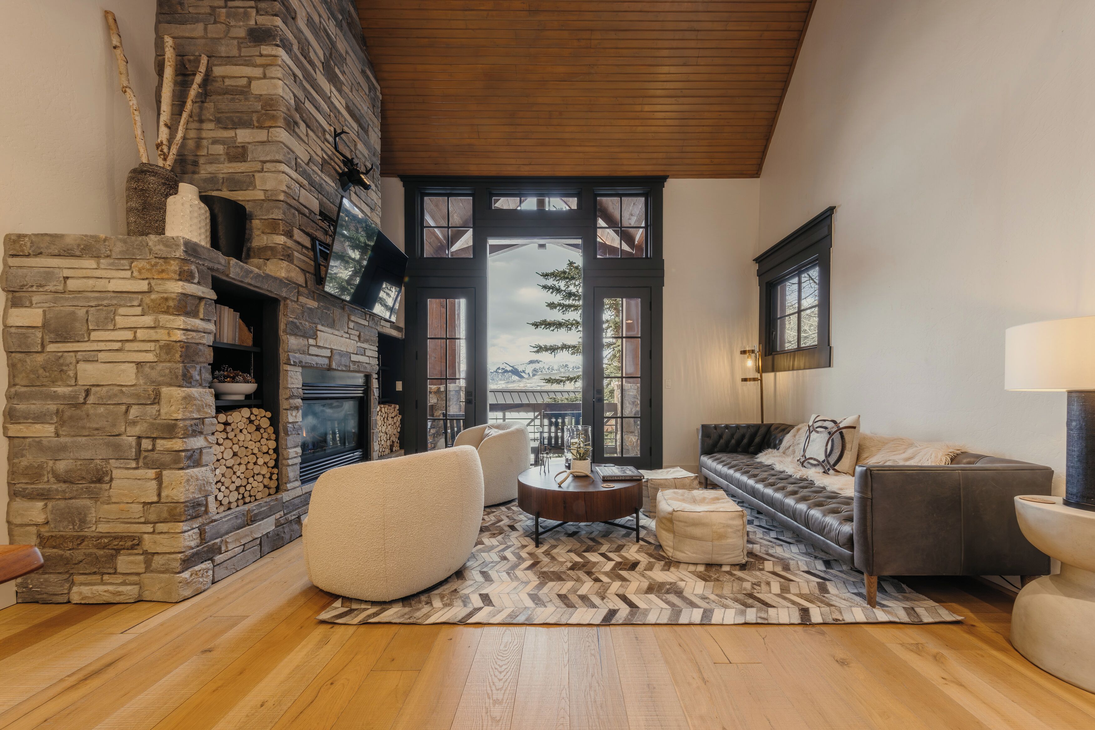 A cozy living room with a stone fireplace, comfortable seating, and a view of the outdoors.