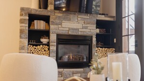 Een stenen openhaard met vuur, omringd door planken met boeken en decoratieve objecten.