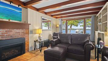 A living room with a fireplace, leather sofa, and a view of the lake.