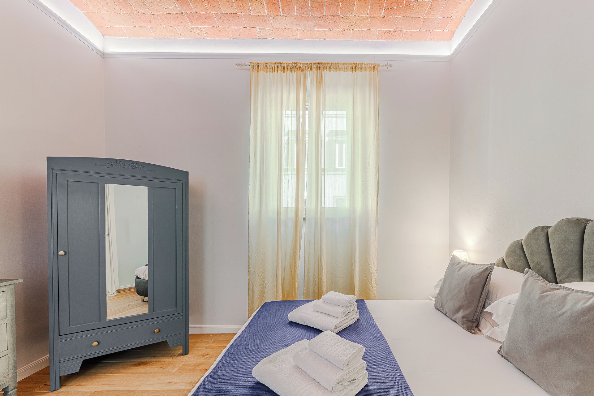 A bedroom with a bed, a wardrobe, and a window with curtains.