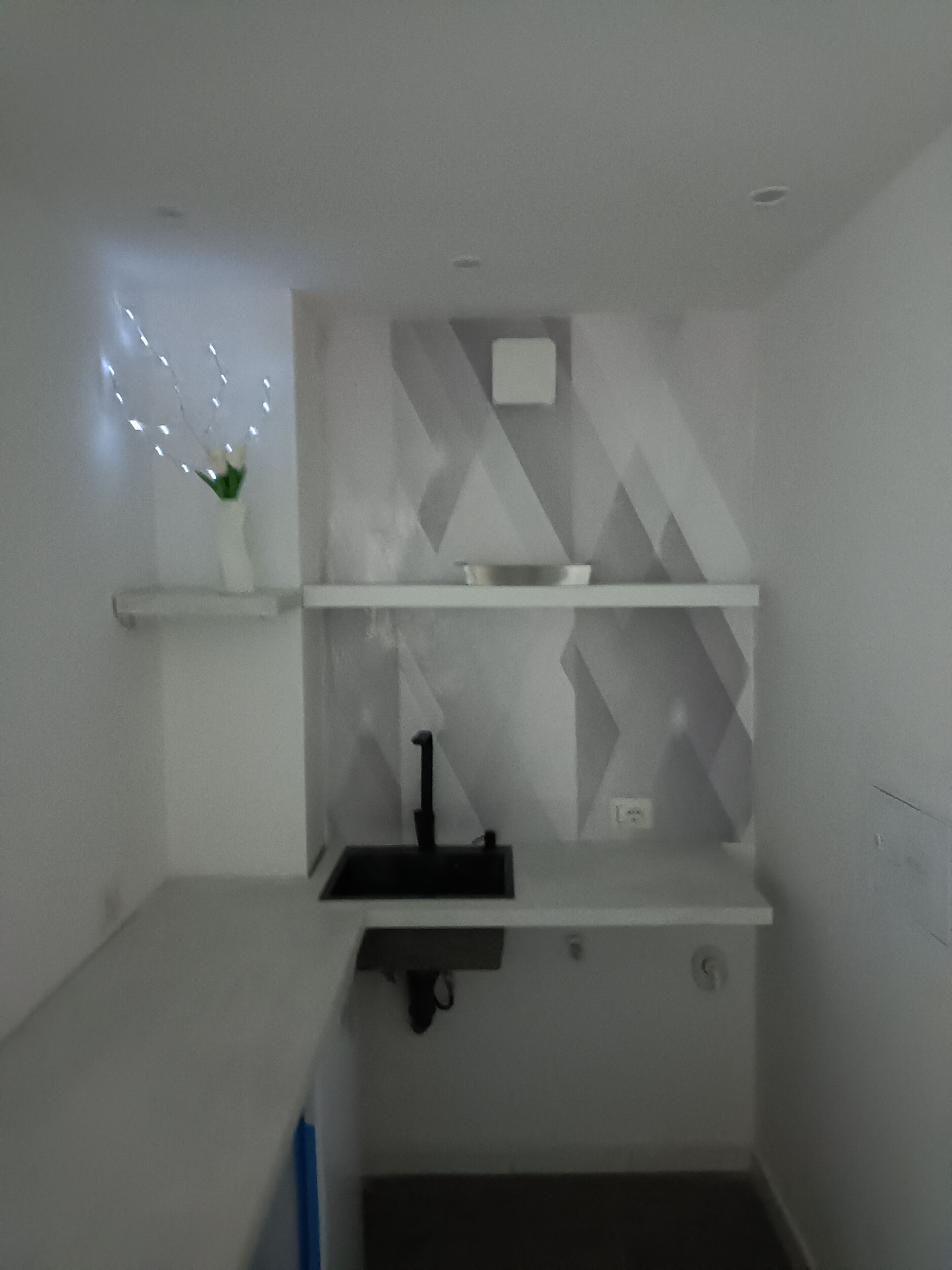 A small, modern bathroom with a white vanity, a black sink, and a decorative light fixture.