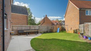 A backyard with a wooden deck, a bench, a slide, and a brick house. - Pass the Keys | Spacious, Modern Family Home - 20 mins to Oxford (Marcham)