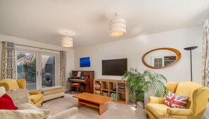 Sala de estar com piano, sofá, mesa de centro e estante.