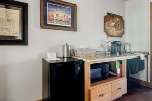 A kitchen with a built-in dishwasher, a coffee maker, and a kettle on the counter. There are framed pictures on the wall.