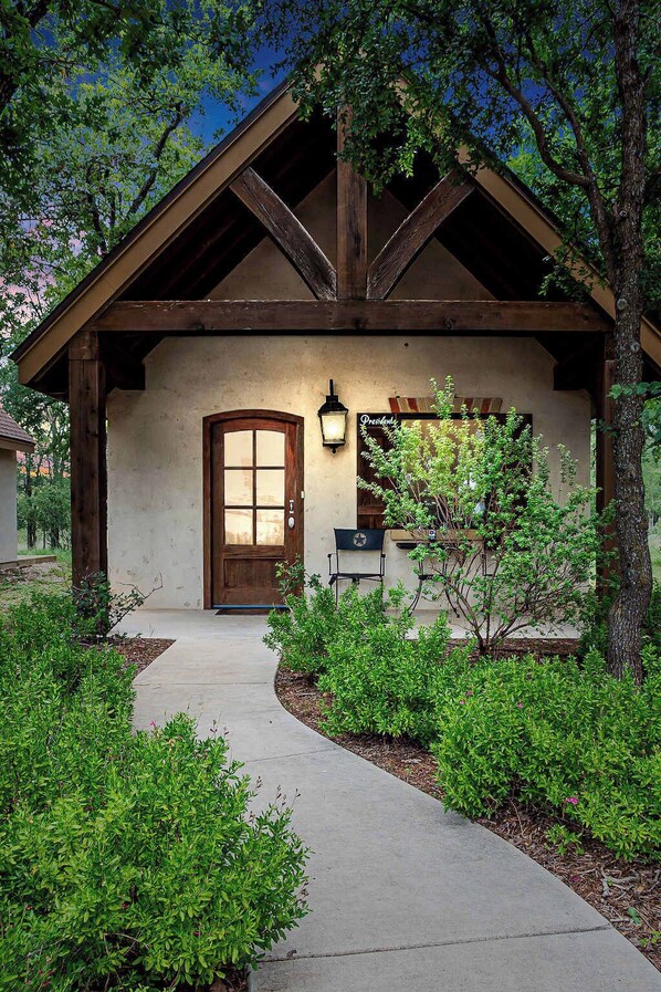 A rustic building with a wooden front door, a small porch, and a well-maintained garden.