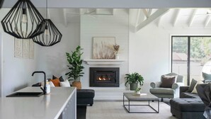 A modern living room with a fireplace, seating area, and a kitchen counter. - Homestead on Fennell - Fresh Eggs, Farm & BBQ Fun (Blackalls Park)