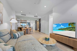 Una sala de estar moderna con un televisor de pantalla plana grande, un sofá, una mesa de centro y un comedor con sillas y una mesa.