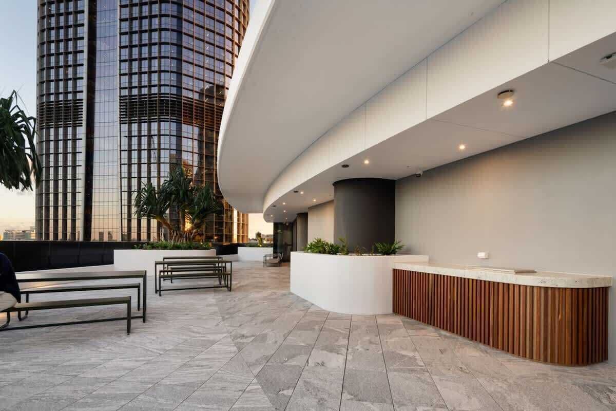 Een moderne receptie met een gebogen witte balie, zitplaatsen en uitzicht op een hoog gebouw.