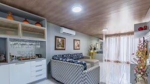 A modern living room with a sofa, a coffee table, and a dining area with a glass-top table. - Livia Cristina  (Barra de Santo Antônio)
