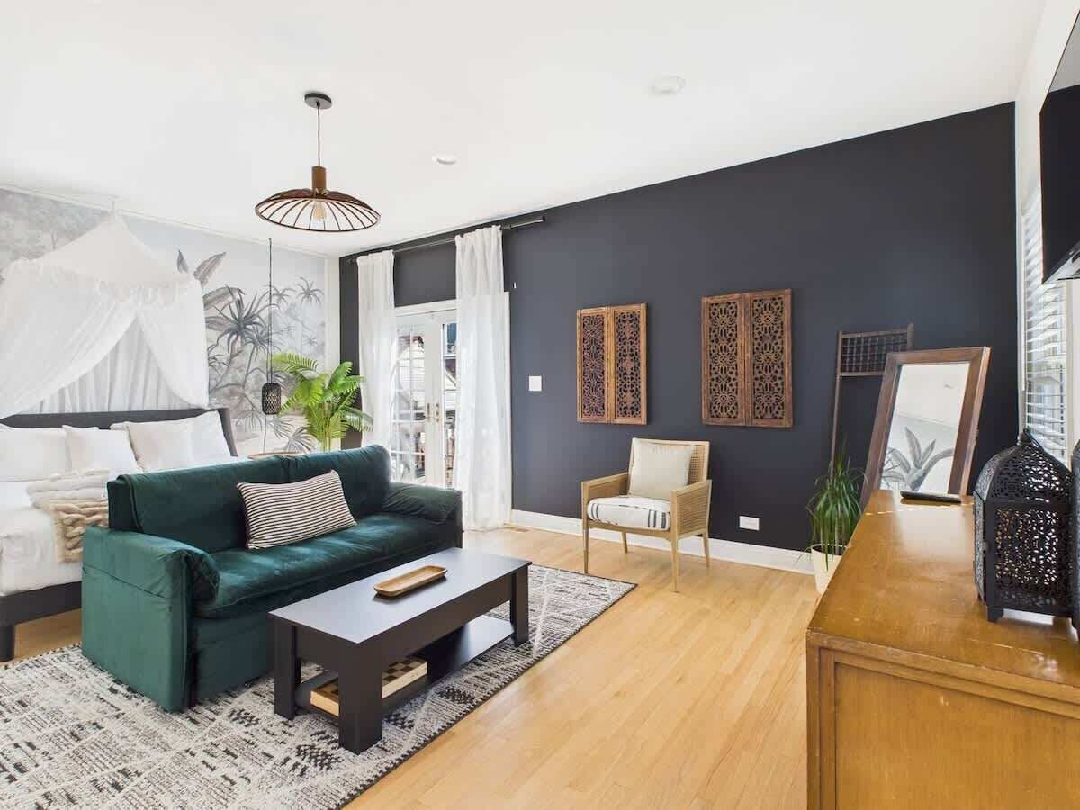 Een woonkamer met een groene bank, een houten salontafel, een stoel en decoratieve panelen aan de muur.