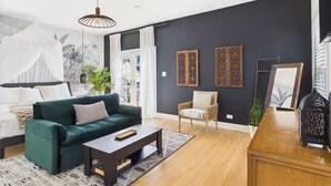 A living room with a green sofa, a wooden coffee table, a chair, and decorative panels on the wall.
