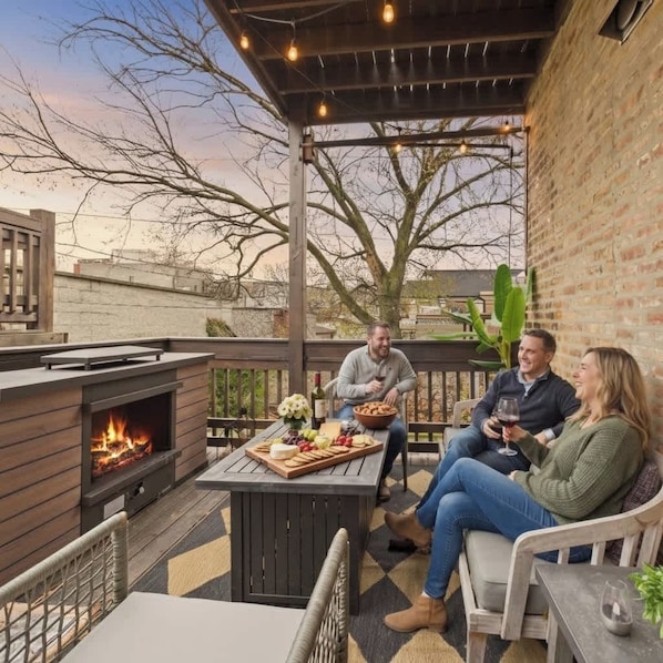 Un patio con chimenea, mobiliario exterior y una mesa con comida y bebidas.