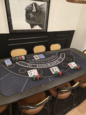 A blackjack table with cards and chips, a framed picture on the wall, and a woven basket.