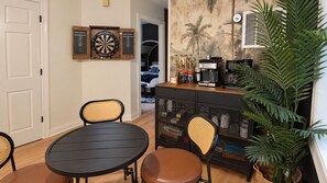 Una habitación con una mesa de comedor, sillas, una máquina de café, un armario y una planta en maceta.