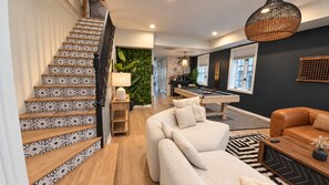 Una escalera con baldosas estampadas, una mesa de billar, un sofá y una mesa de centro en un salón moderno.