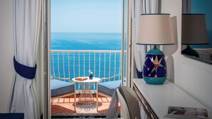 Un balcon avec vue sur la mer, une table ornée d’un vase et une lampe placée sur le côté.