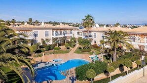 A resort with a swimming pool, palm trees, and a clear blue sky. - NEW! Spacious two-bedroom apartment. 2 terraces, pool, 10 minutes to the beach. (Lote 78, Bloco D.)