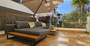 A modern outdoor seating area with a sofa, wooden bench, and a table.
