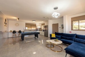 Ein modernes Wohnzimmer mit einem Billardtisch, einem blauen Sofa und einem runden Couchtisch.