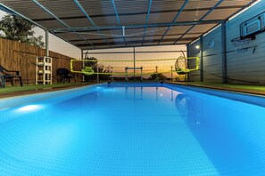 Piscina interior con techo, aro de baloncesto y escalera.