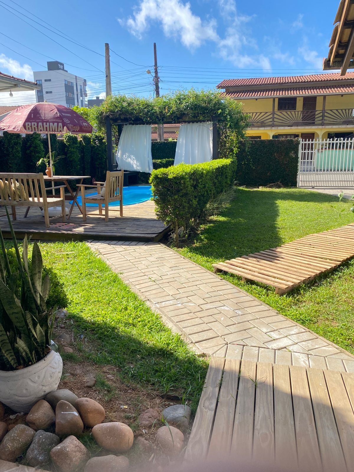 Um quintal com deck de madeira, uma piscina pequena e um espaço de varanda com móveis de exterior.