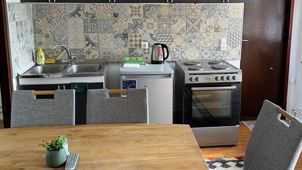 A modern kitchen with dark cabinets, a patterned backsplash, and a stove. - A Peaceful and Spacious Getaway in Sarajevo (Sarajevo)