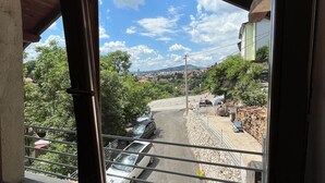 A view from a window with a wooden frame, overlooking a street with parked cars and a building with a green roof. - A Peaceful and Spacious Getaway in Sarajevo (Sarajevo)