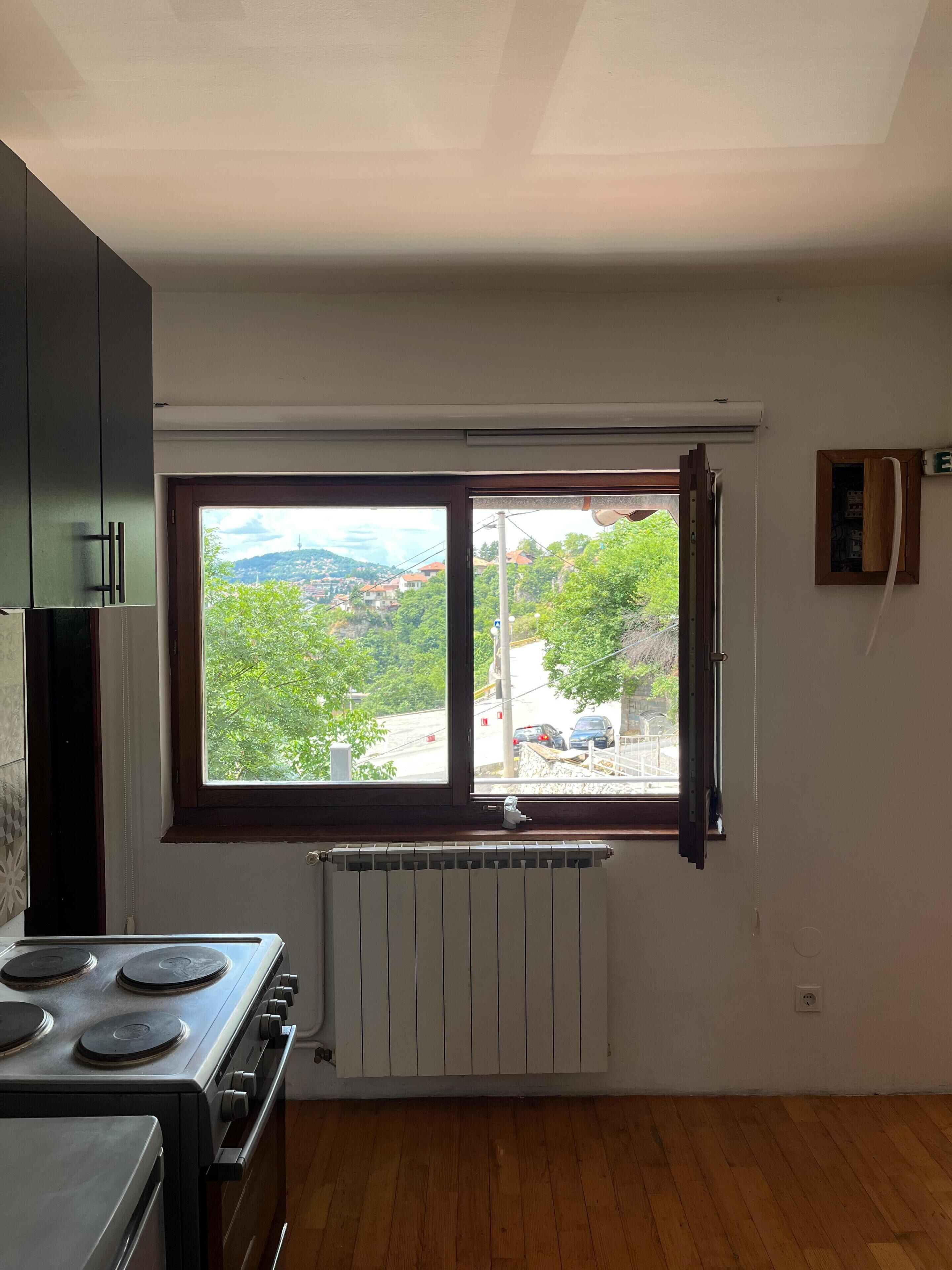 A kitchen with a large window, a stove, and a radiator.
