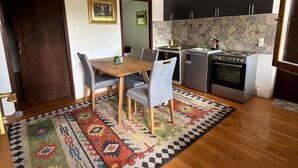 A compact kitchen with dark cabinets, a wooden dining table, and a patterned rug. - A Peaceful and Spacious Getaway in Sarajevo (Sarajevo)