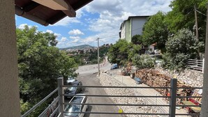 A balcony with a view of a street, parked cars, and a pile of firewood. - A Peaceful and Spacious Getaway in Sarajevo (Sarajevo)