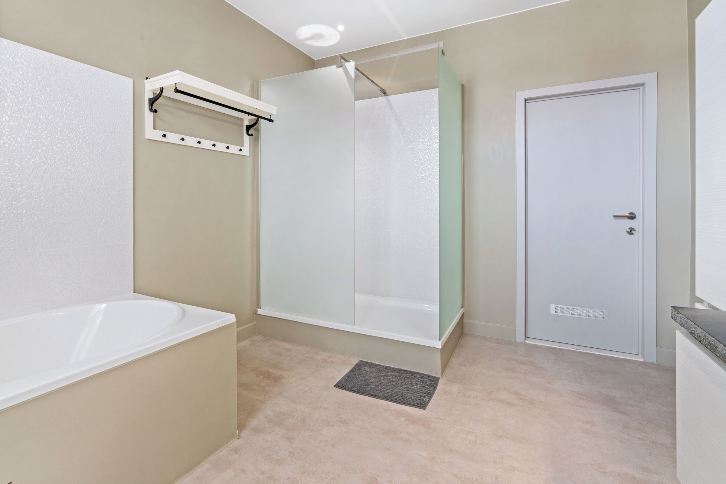 Une salle de bain avec une baignoire, une cabine de douche en verre, une porte blanche et un porte-serviettes.