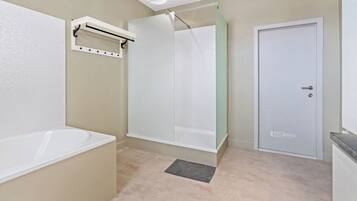 Une salle de bain avec une baignoire, une cabine de douche en verre, une porte blanche et un porte-serviettes.