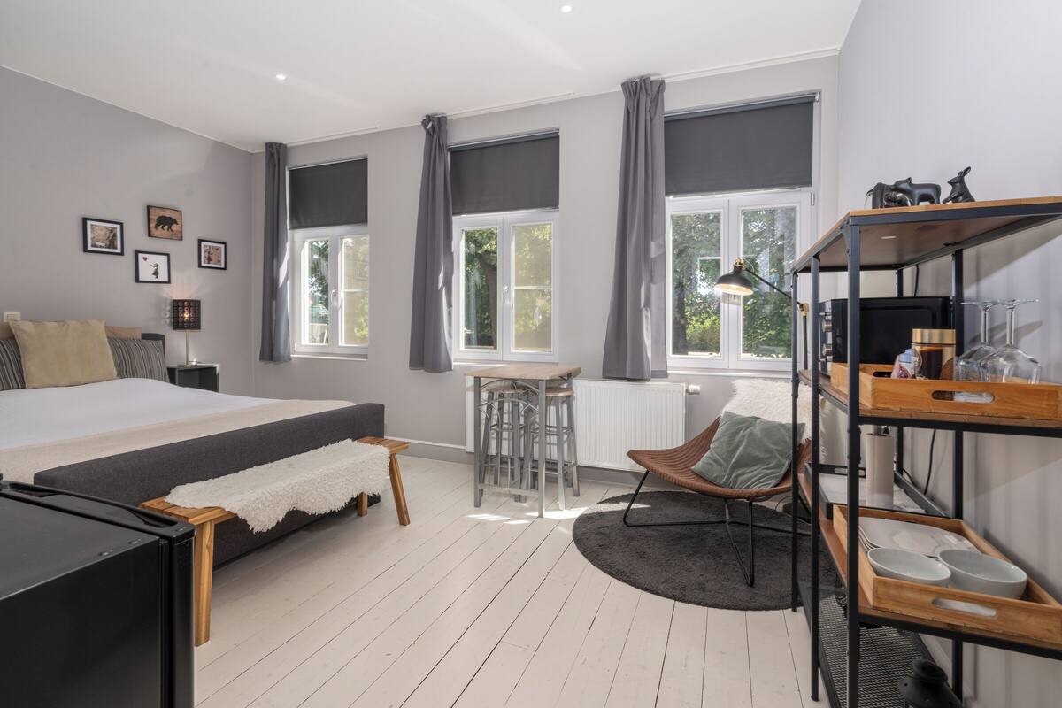 Een moderne slaapkamer met een groot bed, een eettafel en een zithoek.