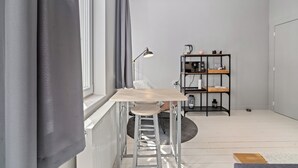 Une pièce moderne avec un bureau en bois, un tabouret-échelle, une étagère en métal noir et un radiateur.