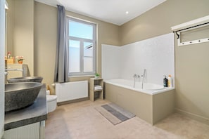 Une salle de bain moderne avec une baignoire sur pieds, un grand lavabo et des toilettes.