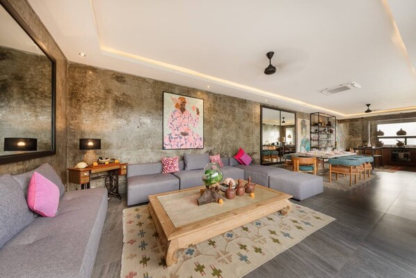 A modern living room with a grey sofa, a wooden coffee table, and a patterned rug.
